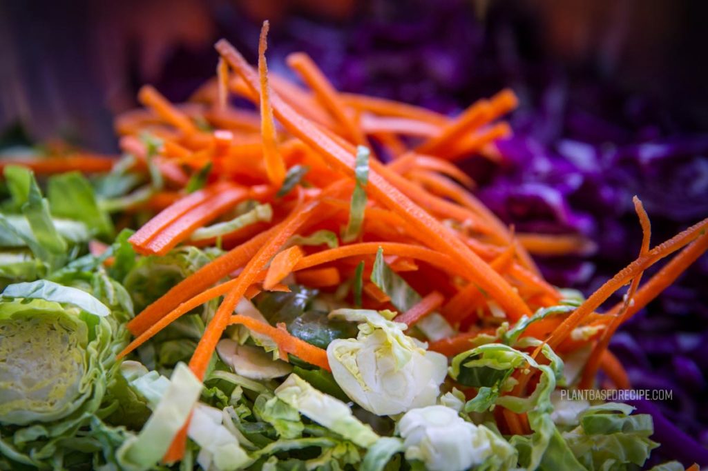 Julienned carrots, brussel sprouts, and cabbage in a bowl