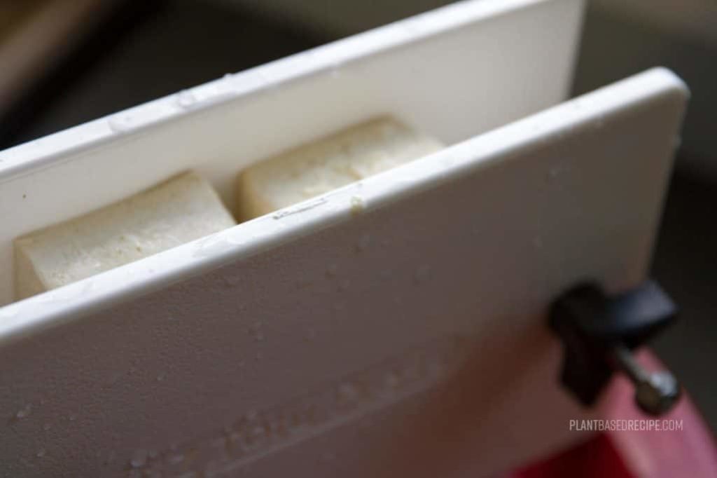 Tofu being pressed in a tofu press